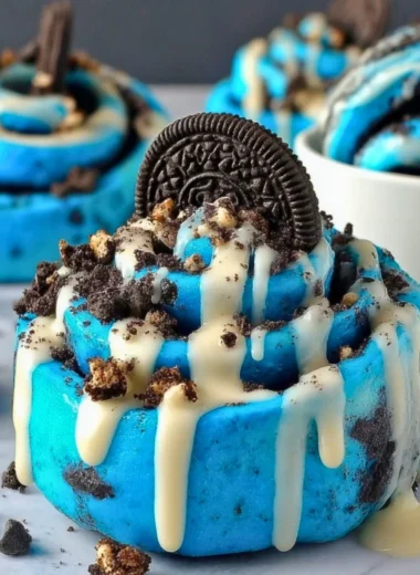 Delicious Cookie Monster cinnamon rolls with blue swirl topped with icing.