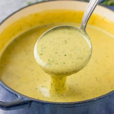 Bowl of creamy zucchini soup garnished with fresh herbs.