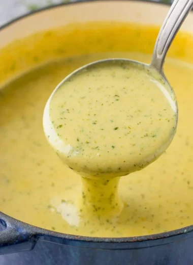 Bowl of creamy zucchini soup garnished with fresh herbs.