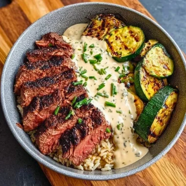 Grilled Steak Bowl with sauce and grilled zucchini on a wooden table