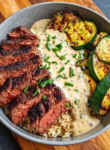Grilled Steak Bowl with sauce and grilled zucchini on a wooden table