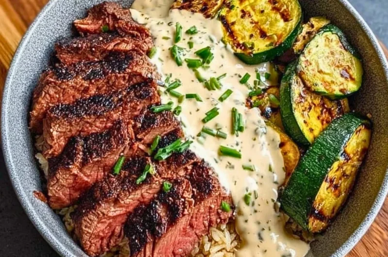 Grilled Steak Bowl with sauce and grilled zucchini on a wooden table