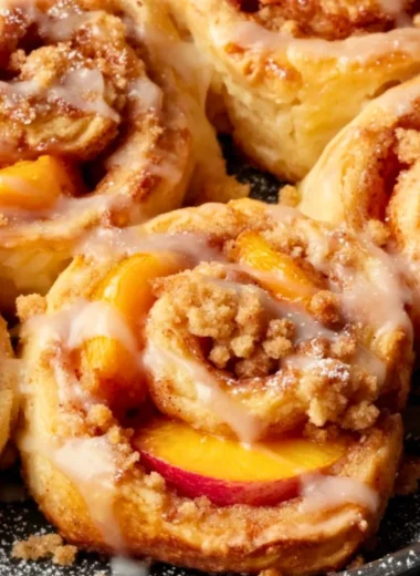 Delicious Peach Cobbler Cinnamon Rolls served on a plate with fresh peaches