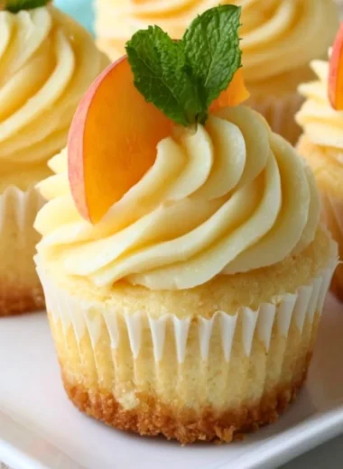 Peach and honey cheesecake cupcakes topped with creamy frosting and fresh peach slices.
