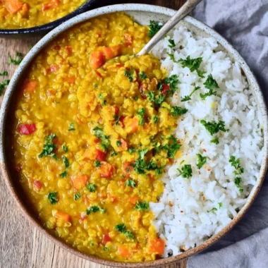 Bowl of vibrant Red Lentil Dahl topped with fresh herbs and spices