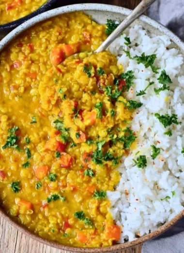 Bowl of vibrant Red Lentil Dahl topped with fresh herbs and spices