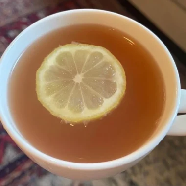 A refreshing glass of Citrus Mint Peach Tea garnished with mint leaves and peach slices.