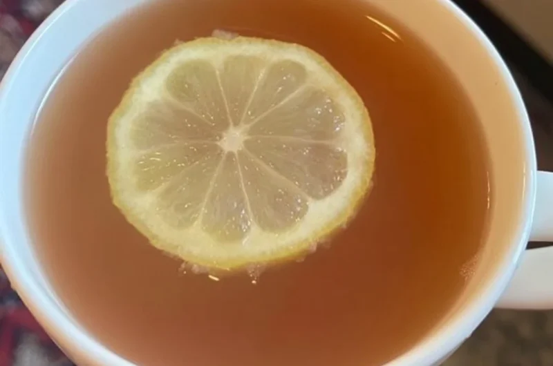 A refreshing glass of Citrus Mint Peach Tea garnished with mint leaves and peach slices.