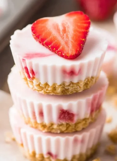 Frozen strawberry yogurt bites on a plate garnished with fresh strawberries