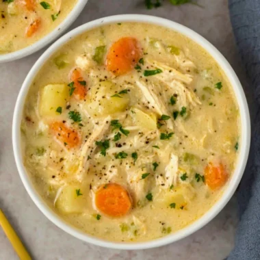 High Protein Chicken Pot Pie Soup in a colorful bowl garnished with herbs.