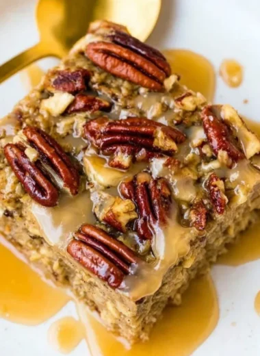 Maple Pecan Baked Oatmeal topped with pecans and maple syrup in a baking dish