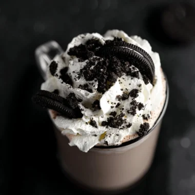A cup of Oreo hot chocolate topped with whipped cream and crushed Oreo cookies