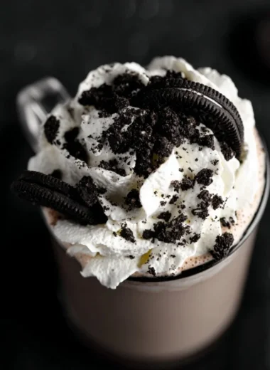 A cup of Oreo hot chocolate topped with whipped cream and crushed Oreo cookies