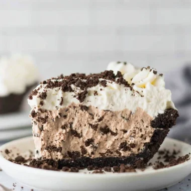Delicious slice of Oreo Pudding Pie topped with whipped cream and chocolate shavings