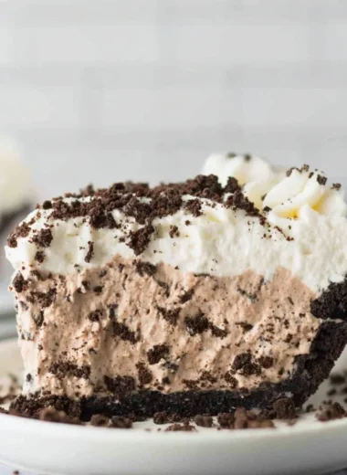 Delicious slice of Oreo Pudding Pie topped with whipped cream and chocolate shavings