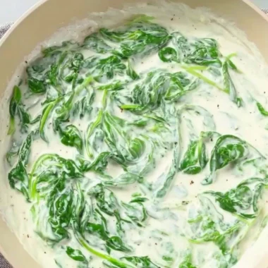 Plate of pasta topped with creamy spinach sauce garnished with herbs