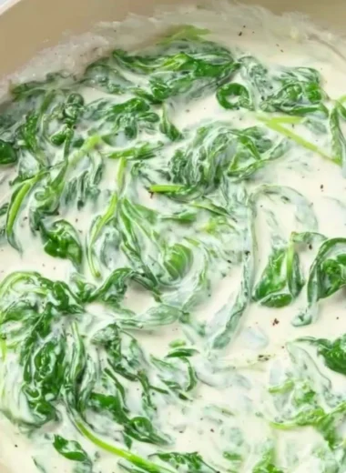 Plate of pasta topped with creamy spinach sauce garnished with herbs