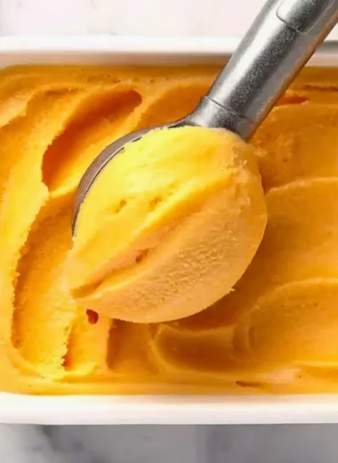Delicious homemade peach sorbet served in a bowl with fresh peaches