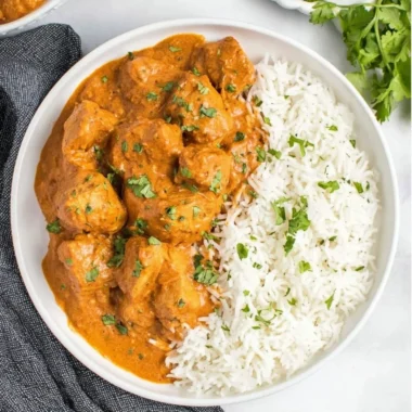 Slow Cooker Butter Chicken served in a bowl with rice and garnish.