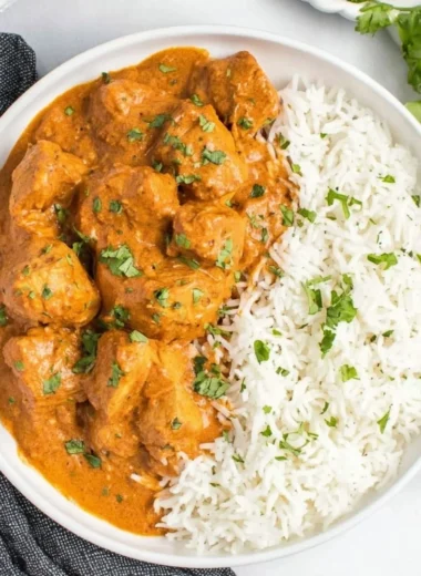 Slow Cooker Butter Chicken served in a bowl with rice and garnish.