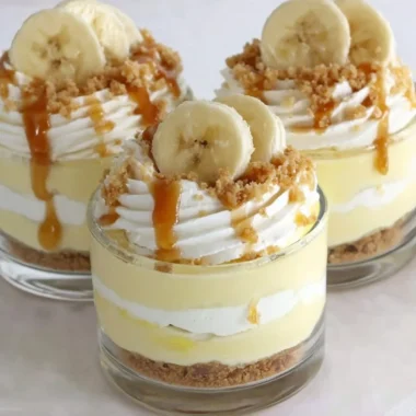 Delicious Banana Caramel Cream Dessert in a glass, topped with whipped cream and banana slices.