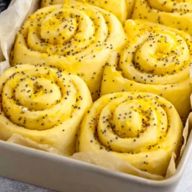 Homemade lemon rolls drizzled with icing on a rustic wooden table