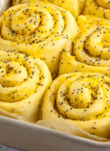 Homemade lemon rolls drizzled with icing on a rustic wooden table