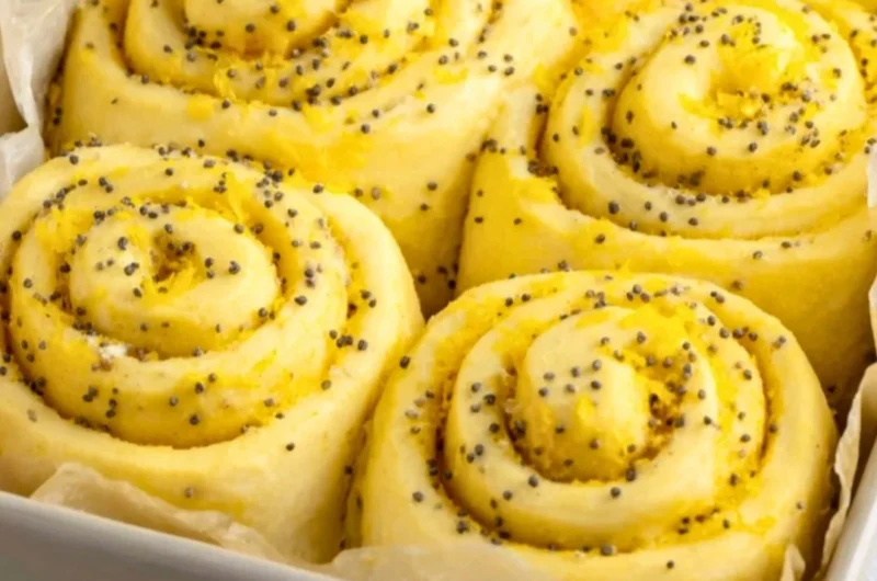 Homemade lemon rolls drizzled with icing on a rustic wooden table