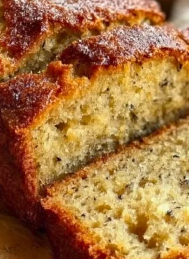 Slice of moist banana bread made with 3 ripe bananas on a wooden board.