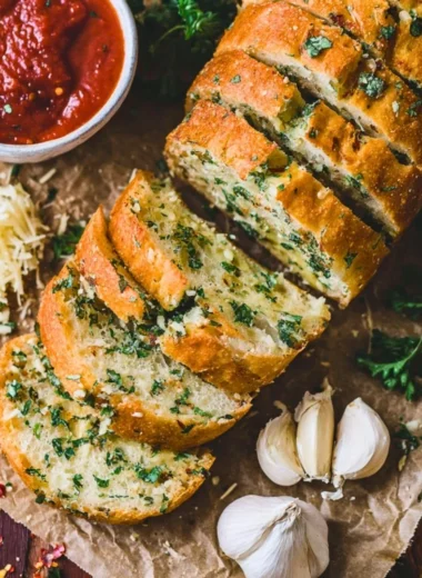 Freshly baked sourdough garlic bread sliced and garnished with herbs