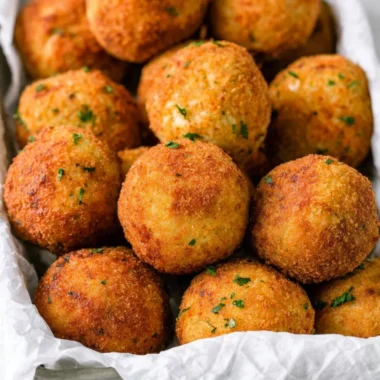 Crispy cheesy rice balls (arancini) served on a plate, garnished with herbs.