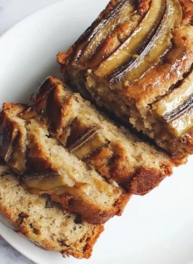 Loaf of classic banana bread fresh out of the oven, sliced on a wooden cutting board