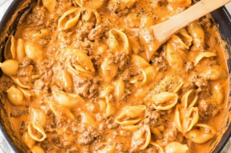Creamy beef and shells dish served in a bowl with herbs on top