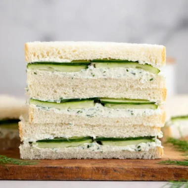 A delicious cucumber sandwich on a plate garnished with herbs.