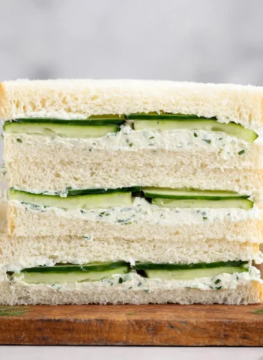 A delicious cucumber sandwich on a plate garnished with herbs.