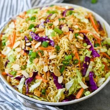 A hearty ramen noodle salad topped with fresh vegetables and a tangy dressing