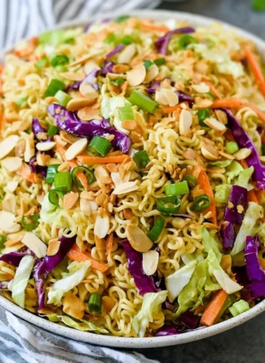 A hearty ramen noodle salad topped with fresh vegetables and a tangy dressing