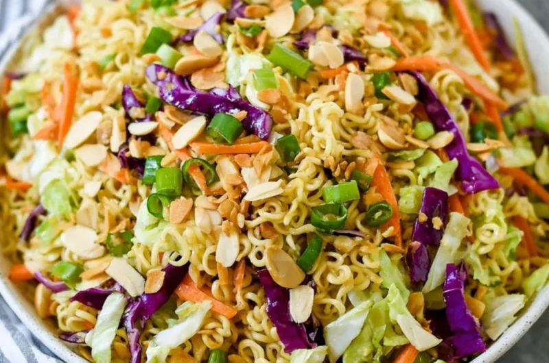 A hearty ramen noodle salad topped with fresh vegetables and a tangy dressing