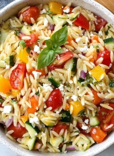 A vibrant bowl of Orzo Salad featuring fresh vegetables and herbs
