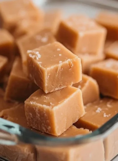 Delicious homemade Peanut Butter Fudge on a wooden table with nuts.
