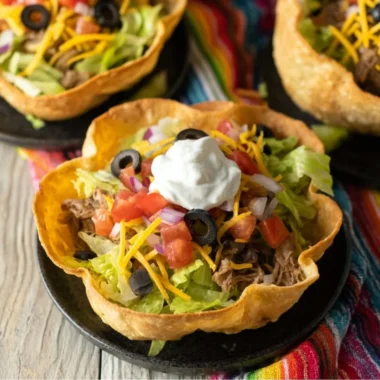 Colorful taco salad bowls filled with fresh ingredients and toppings.