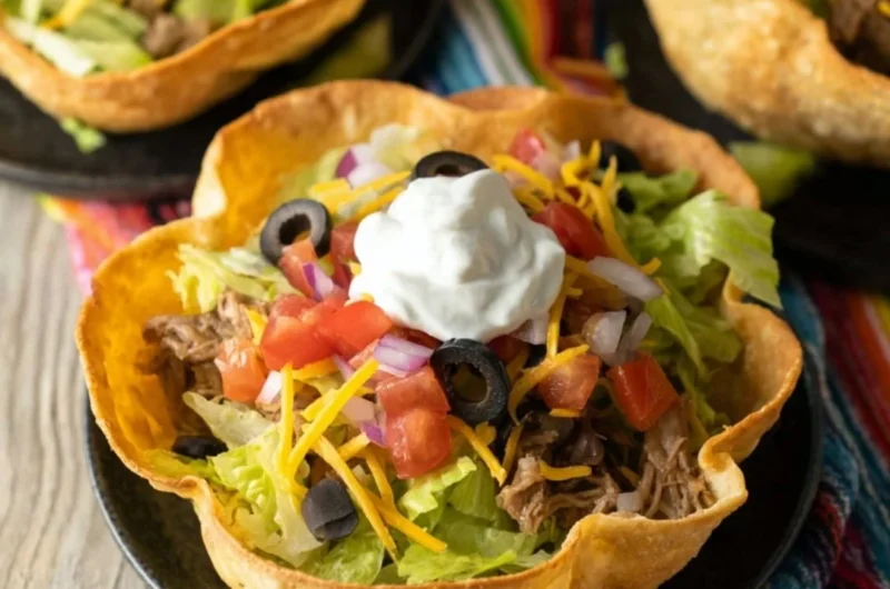 Colorful taco salad bowls filled with fresh ingredients and toppings.