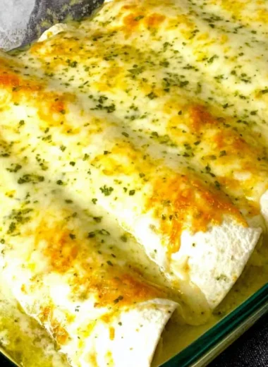 White chicken enchiladas topped with cheese and green sauce