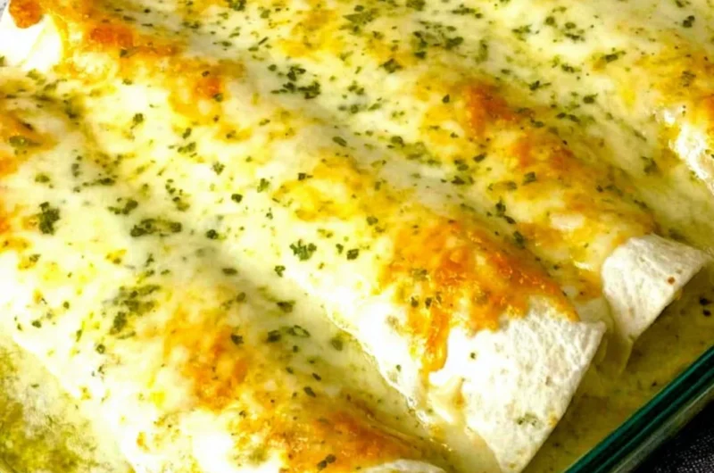 White chicken enchiladas topped with cheese and green sauce