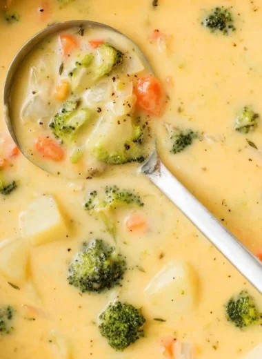 Bowl of creamy broccoli cheese potato soup garnished with cheese and herbs