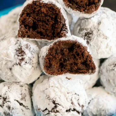 Double chocolate snowball cookies dusted with powdered sugar on a white plate
