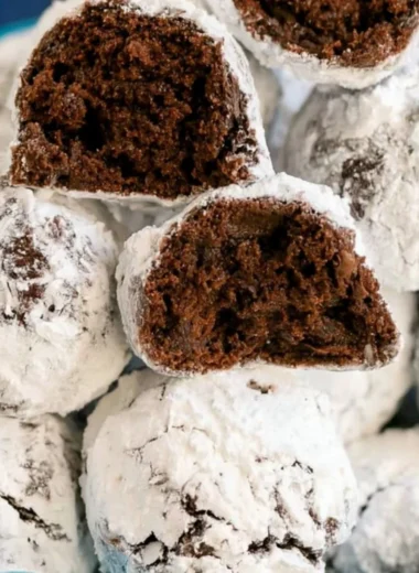 Double chocolate snowball cookies dusted with powdered sugar on a white plate