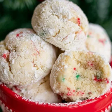 Baked snowball cookies dusted in powdered sugar on a festive plate.