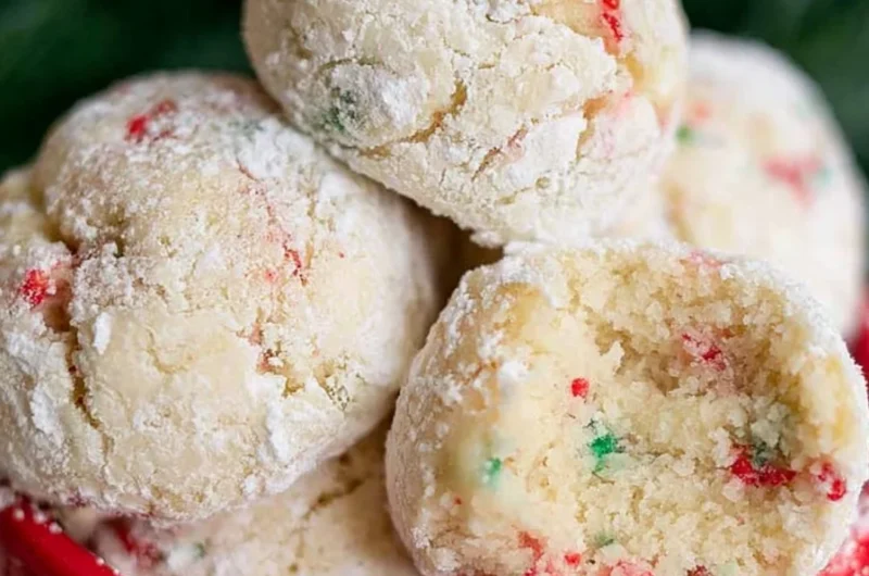 Baked snowball cookies dusted in powdered sugar on a festive plate.